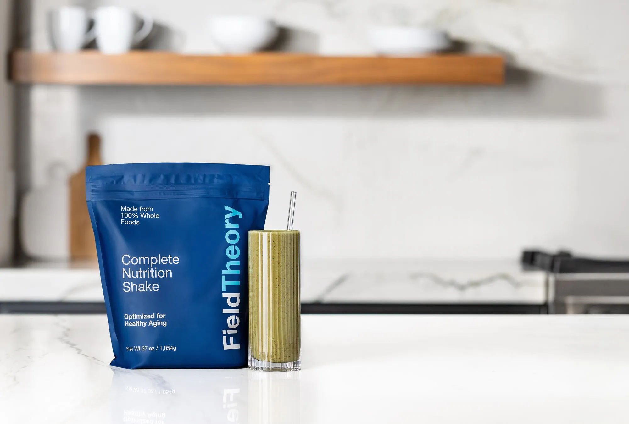 Field Theory pouch beside a glass of the prepared shake on a marble counter