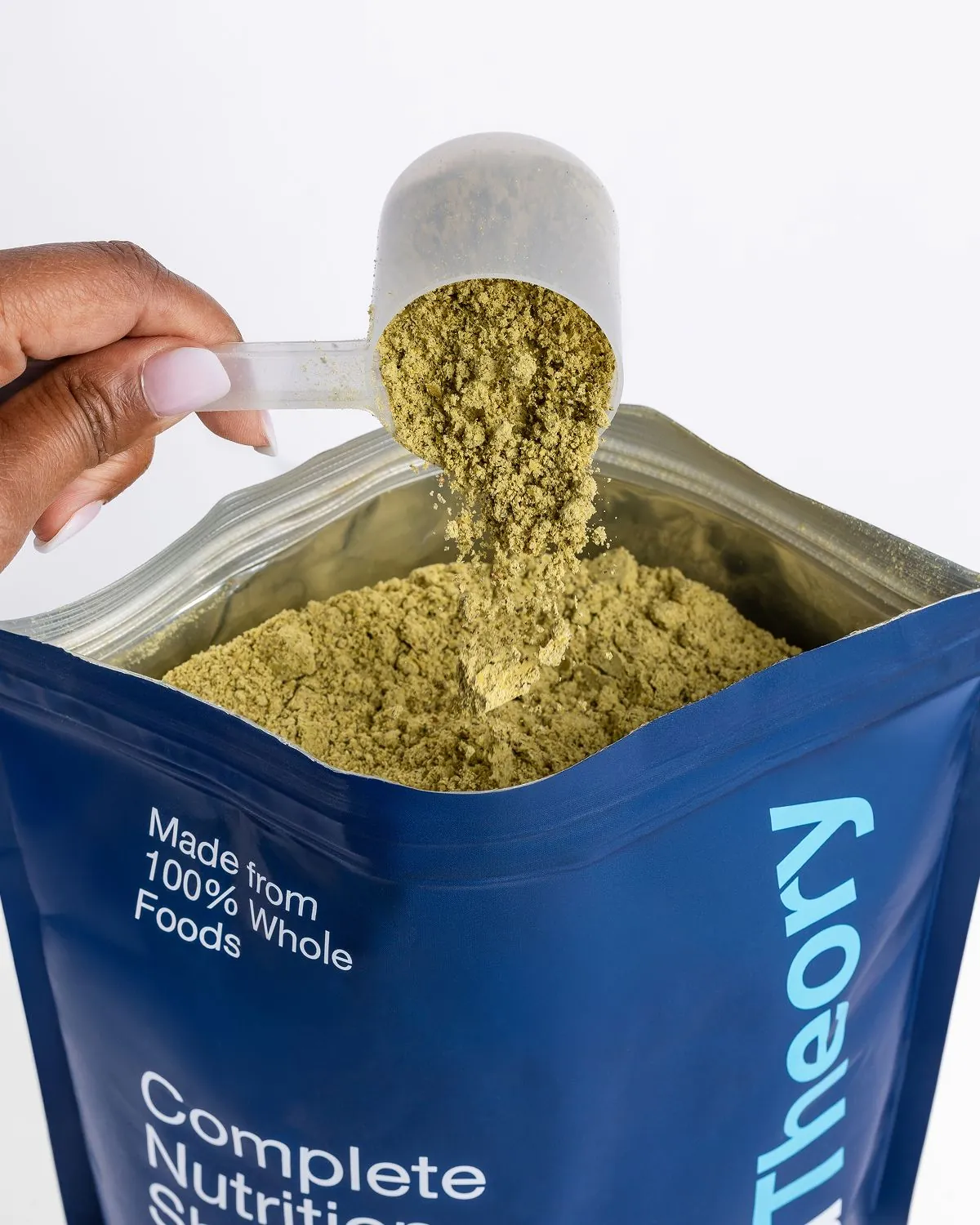A scoop of Field Theory powder being lifted from the pouch