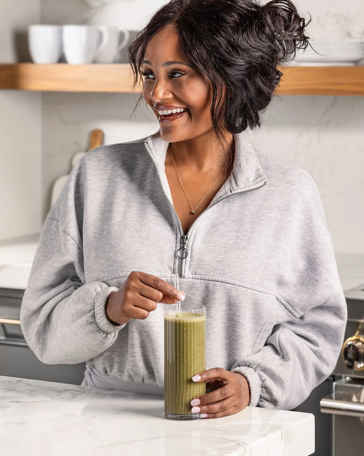 A woman with a glass of Field Theory at a kitchen counter